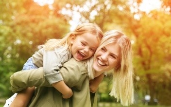 couple with dental implants in Corte Madera pointing to their smiles