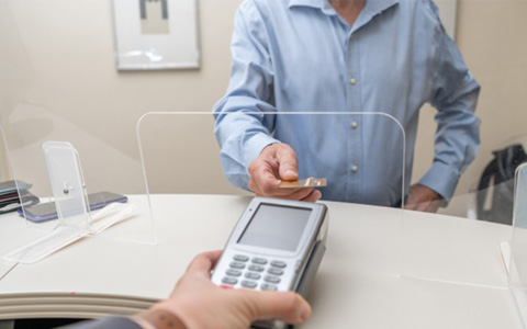  A man paying the cost of dental crowns with a credit card