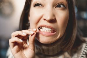 A woman picking her teeth, not showing good dental etiquette