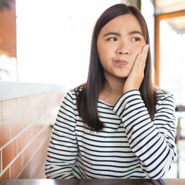 Woman rubbing her aching tooth.