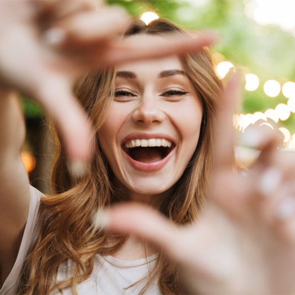 Woman smiling and outlining her mouth with her fingers.